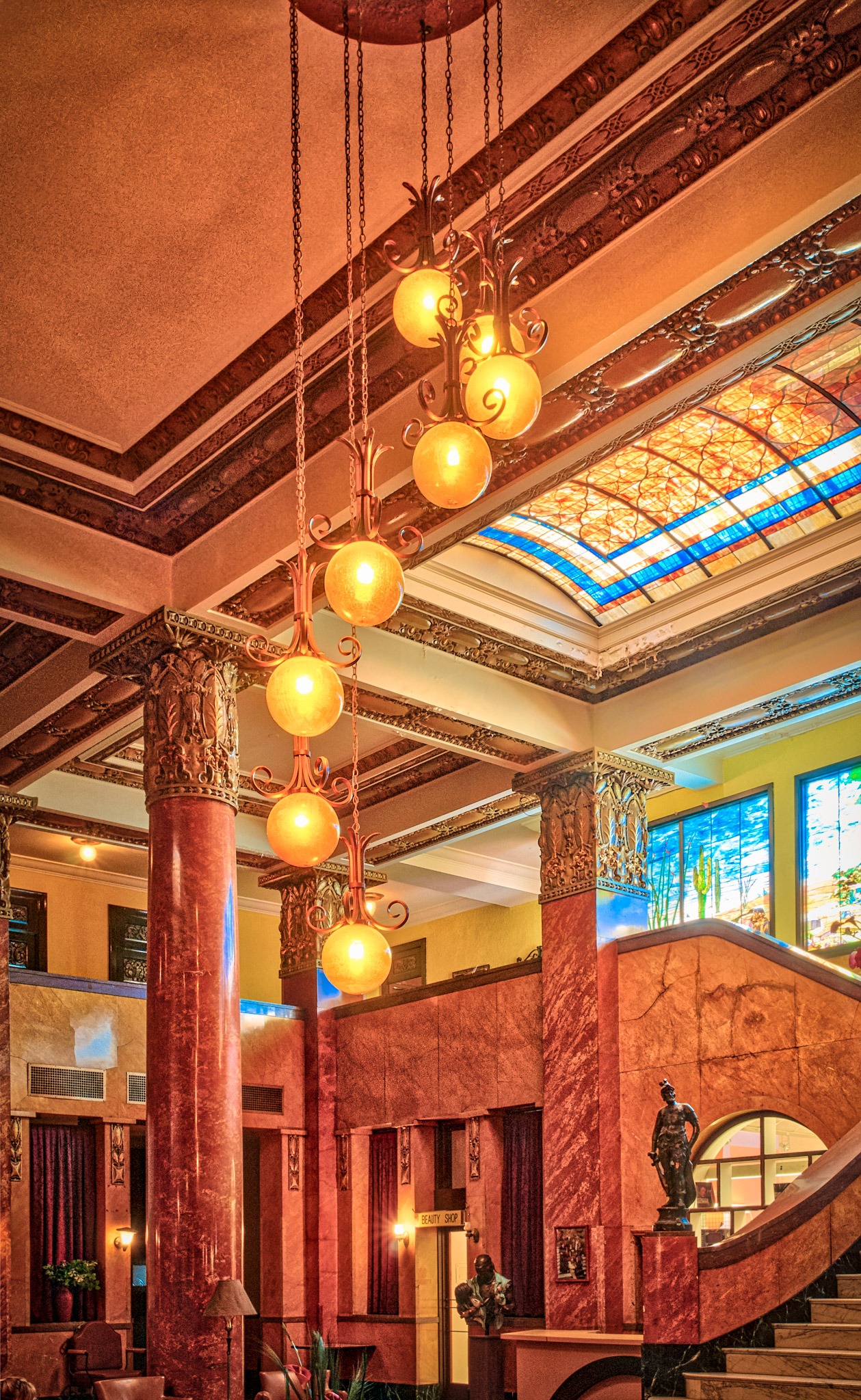 A view of the grand Hotel Gadsden lobby highlighting the leather furniture, tile floors, Italian marble, stained glass, and expansive grand staircase. Notice the spiral central chandelier.