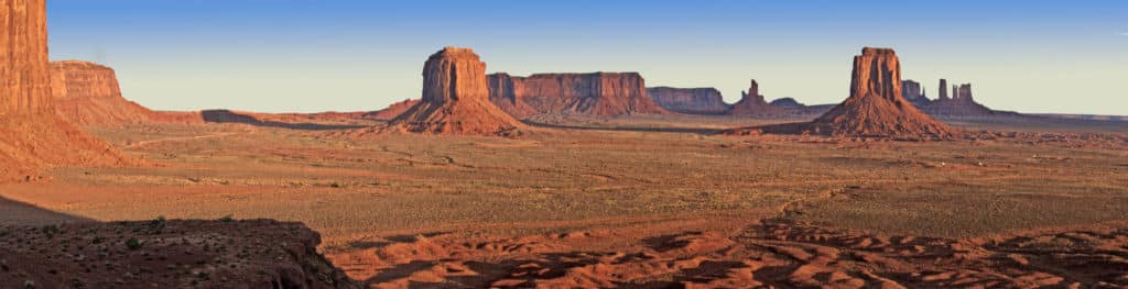 A sunset shot from Artists Point showing a panorama of red rock buttes in Monument Valley Navajo Tribal Park.