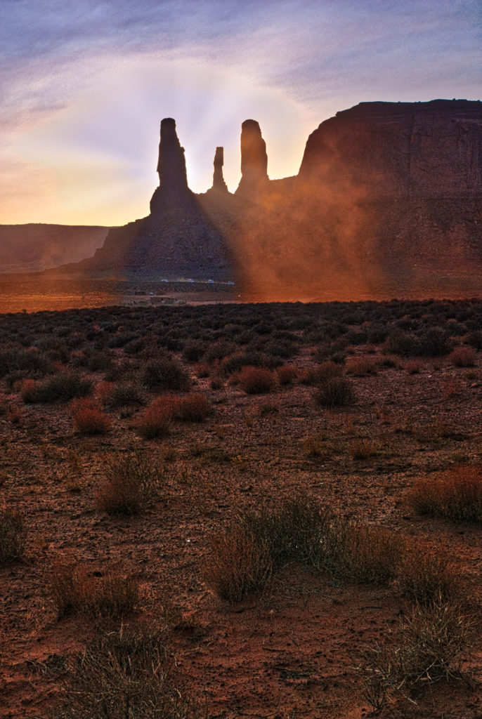 A view of the Three Sisters through a dust devil as seen from the self-guided tour road within the Monument Valley Navajo Tribal Park.