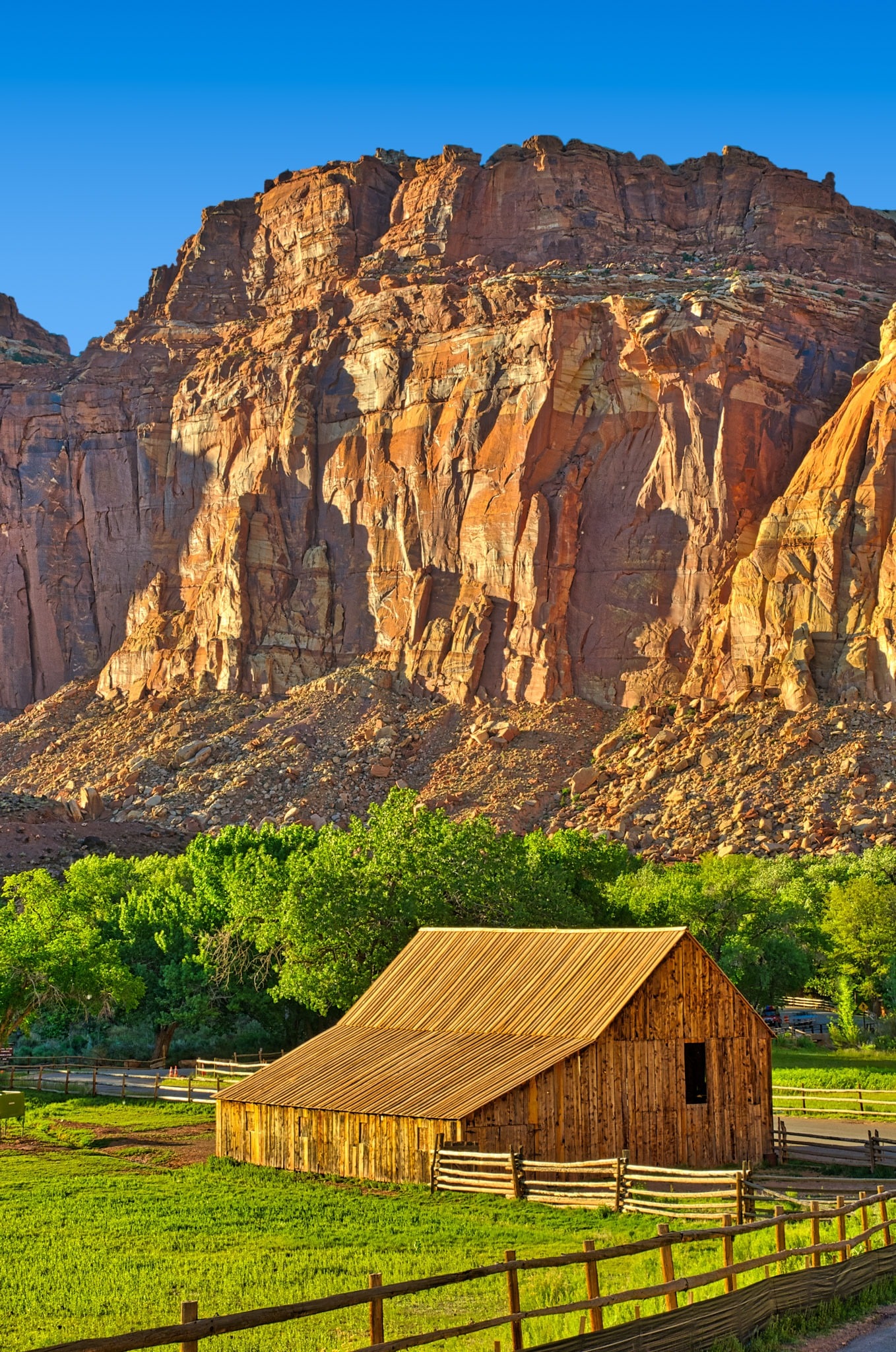 A view of one of the barns on the Gifford Homestead with red cliffs of the Waterpocket Fold in the background, in the Fruita District of Capitol Reef National Park in Utah.