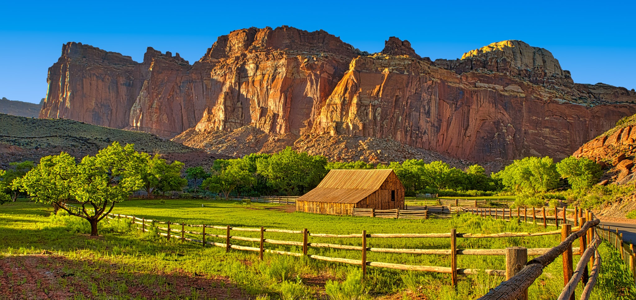 A view of one of the barns on the Gifford Homestead with red cliffs of the Waterpocket Fold in the background, in the Fruita District of Capitol Reef National Park in Utah.