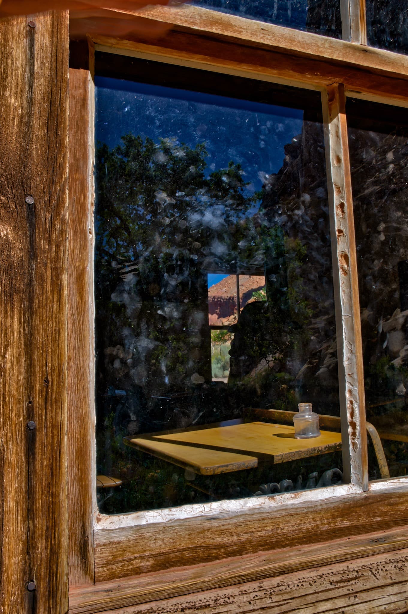 This is a closeup view of a student's desk through a window in the Fruita Schoolhouse, located in Capitol Reef National Park, Utah.