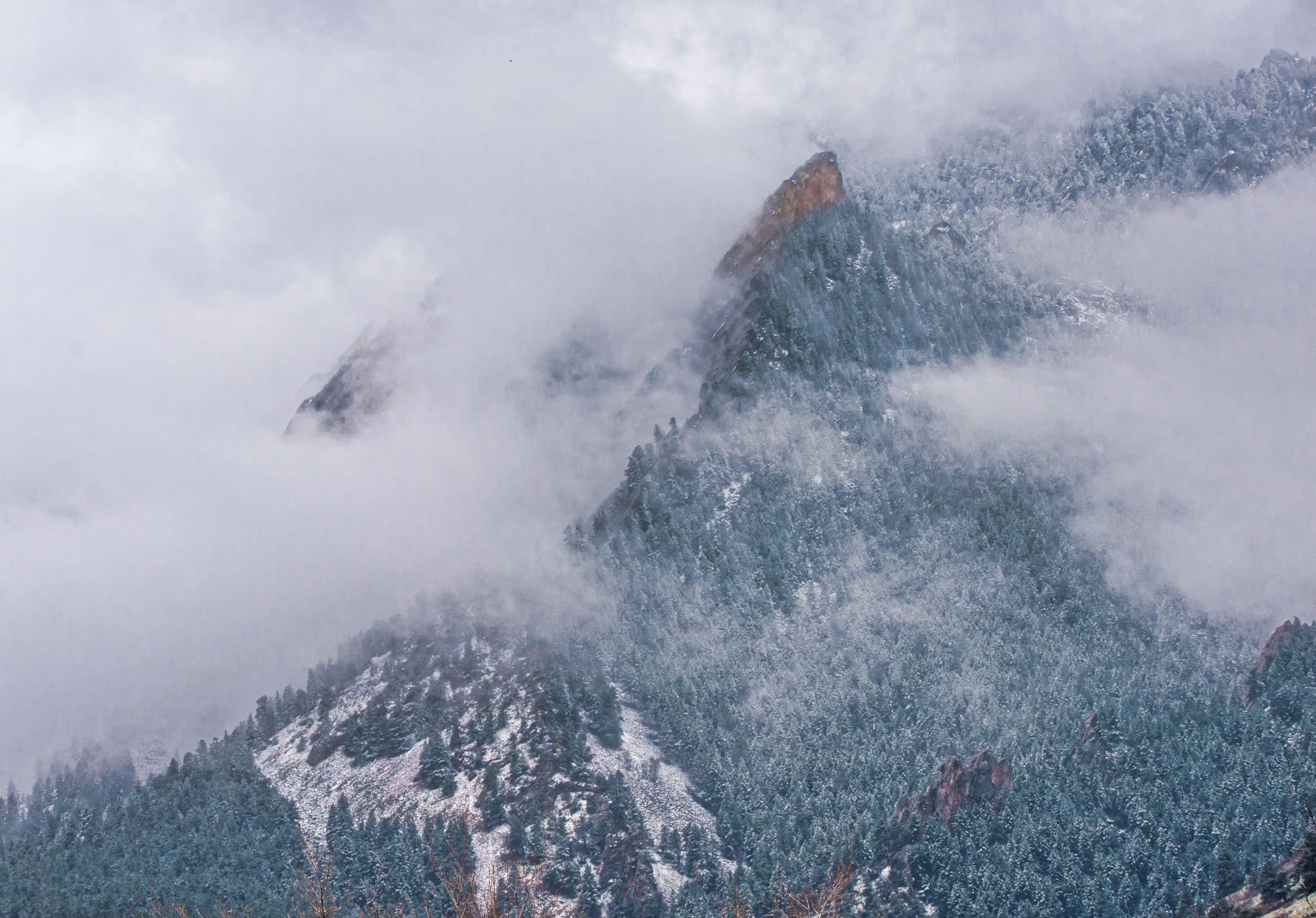 The First Flatiron on the west side of Boulder, Colorado, is barely visible through the snow and clouds.