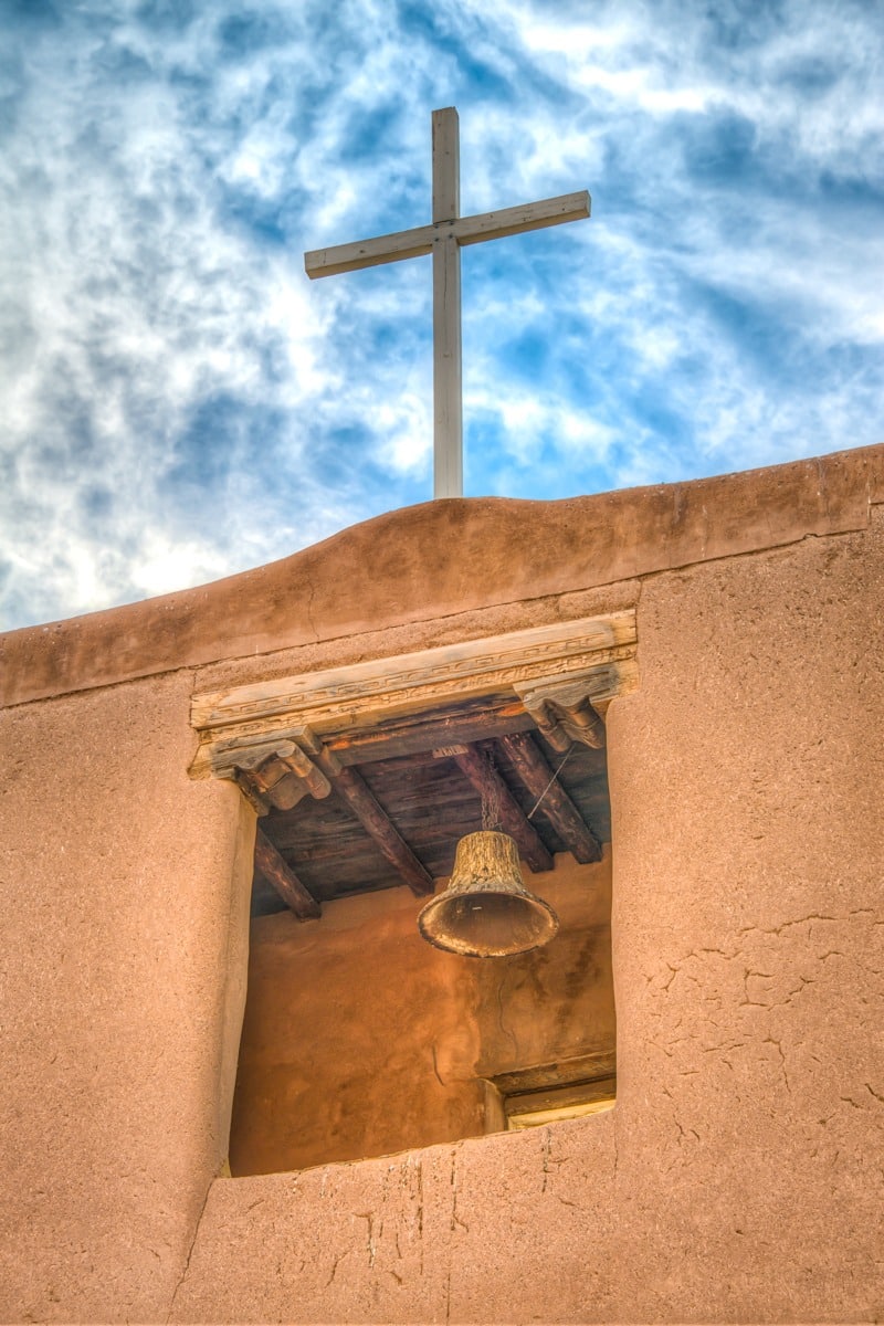 This close-up of the San Miguel Mission bell tower gives the view a closer look at the bell, cross, vigas, and litillas, as well as the corbels and decorated lintel.