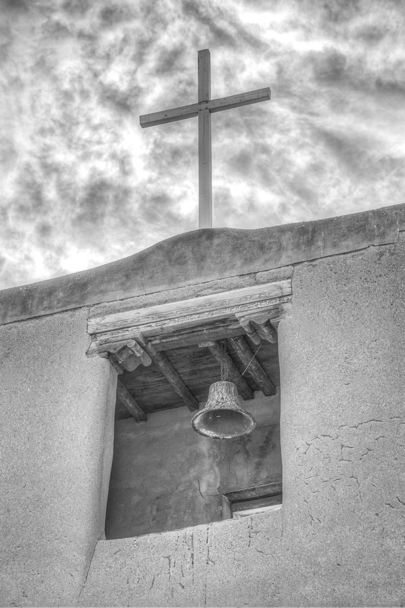 This close-up of the San Miguel Mission bell tower gives the view a closer look at the bell, cross, vigas, and litillas, as well as the corbels and decorated lintel.