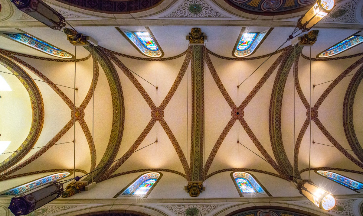 This view, looking up at the ribbed vault, showcases the beautiful stained glass clerestory windows, the richly decorated ribs, and the beautifully painted window casements.
