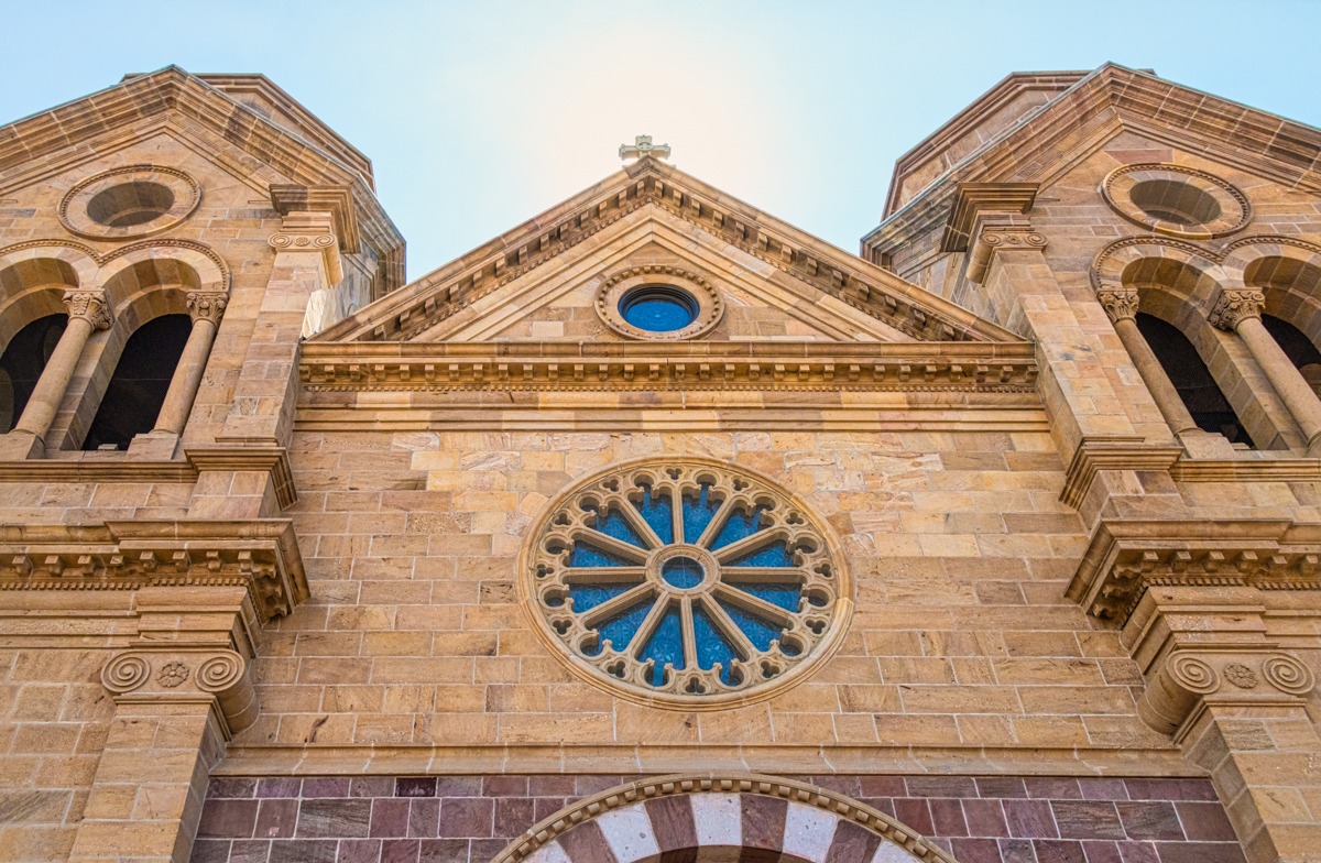This is an exterior view looking up at the rose window above the entrance to Saint Francis Cathedral in Santa Fe, New Mexico. On either side you can see the two bell towers. Due to budgetary contraints, no spires were placed atop the towers. The main building blocks are limestone.