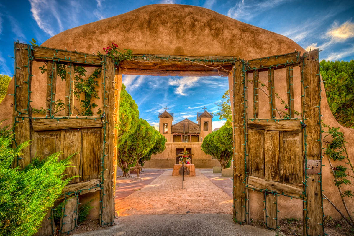 A view through the arched gateway at El Santuario de Chimayó. This Spanish Colonial-style church was built in 1816 and is considered the most popular Catholic pilgrimage shrine in the U.S. The santuario is located in Chimayo, New Mexico. This mission is located along the High Road to Taos.
