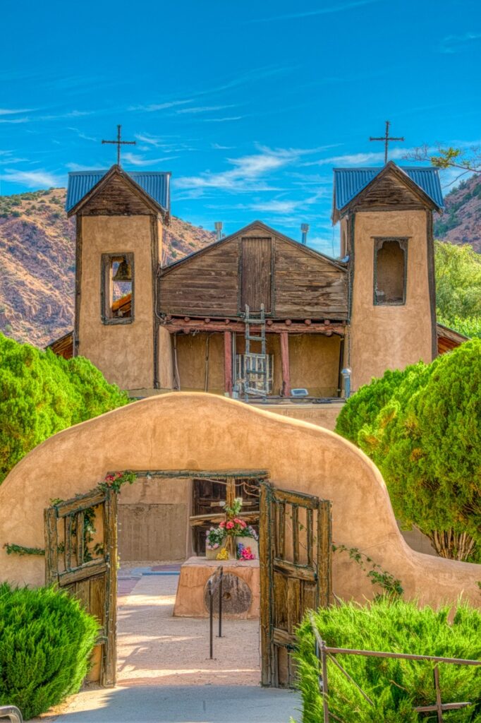 A view through the arched gateway at El Santuario de Chimayó. This Spanish Colonial-style church was built in 1816 and is considered the most popular Catholic pilgrimage shrine in the U.S. The santuario is located in Chimayo, New Mexico.
