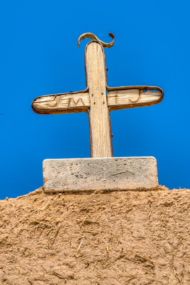 This is a close-up of the cross that is atop the archway of the gate to the church. The San Jose de Gracia Church, also known as Church of Santo Tomas Del Rio de Las Trampas, is a historic church on the main plaza of Las Trampas, New Mexico.