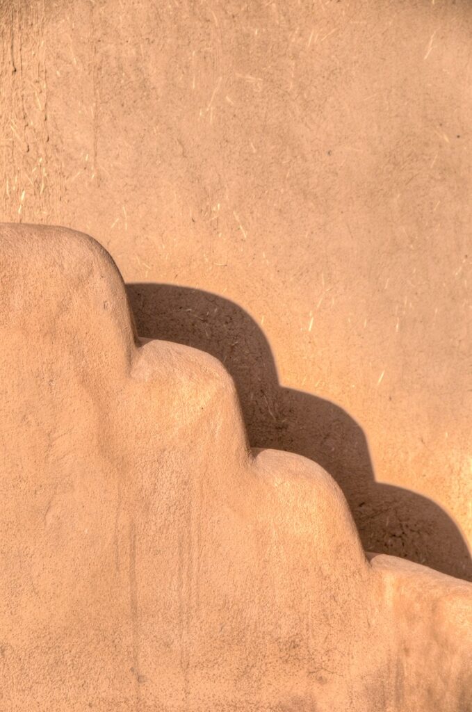 The stepped wall around San Francisco de Asis Mission Church casts a shadow on the wall of the mission.