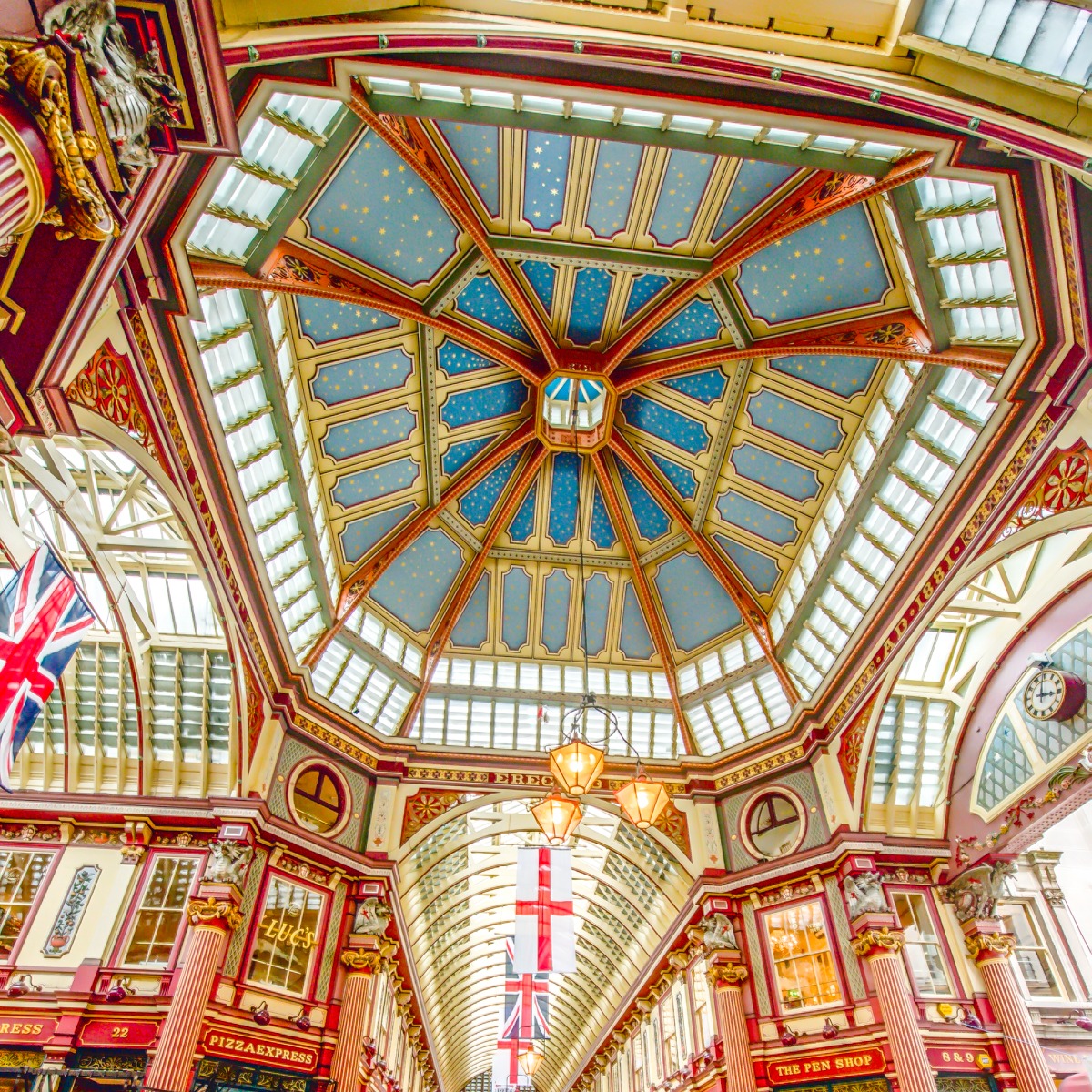 This is the ceiling of the main hall at Leadenhall Market in the City of London. The ornate roof structure, painted green, maroon and cream, and cobbled floors of the current structure were designed in 1881 by Sir Horace Jones.