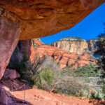 The surrounding red and buff sandstone cliffs are visible from under the overhang of an alcove containing pictographs at Palatki Heritage Site near Sedona, Arizona.