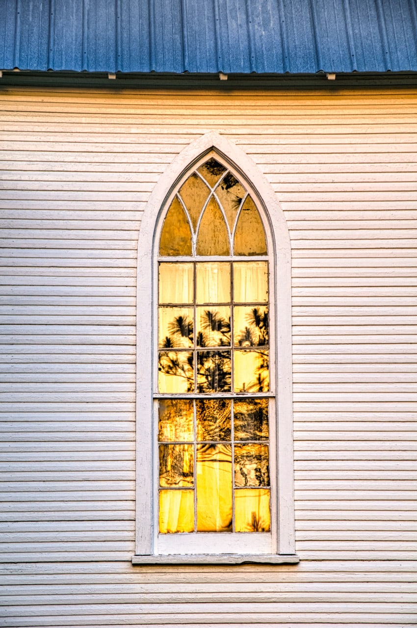 A pine tree is reflected in a window on the west side of the former St. Mary's Episcopal Church in Evergreen, Alabama.