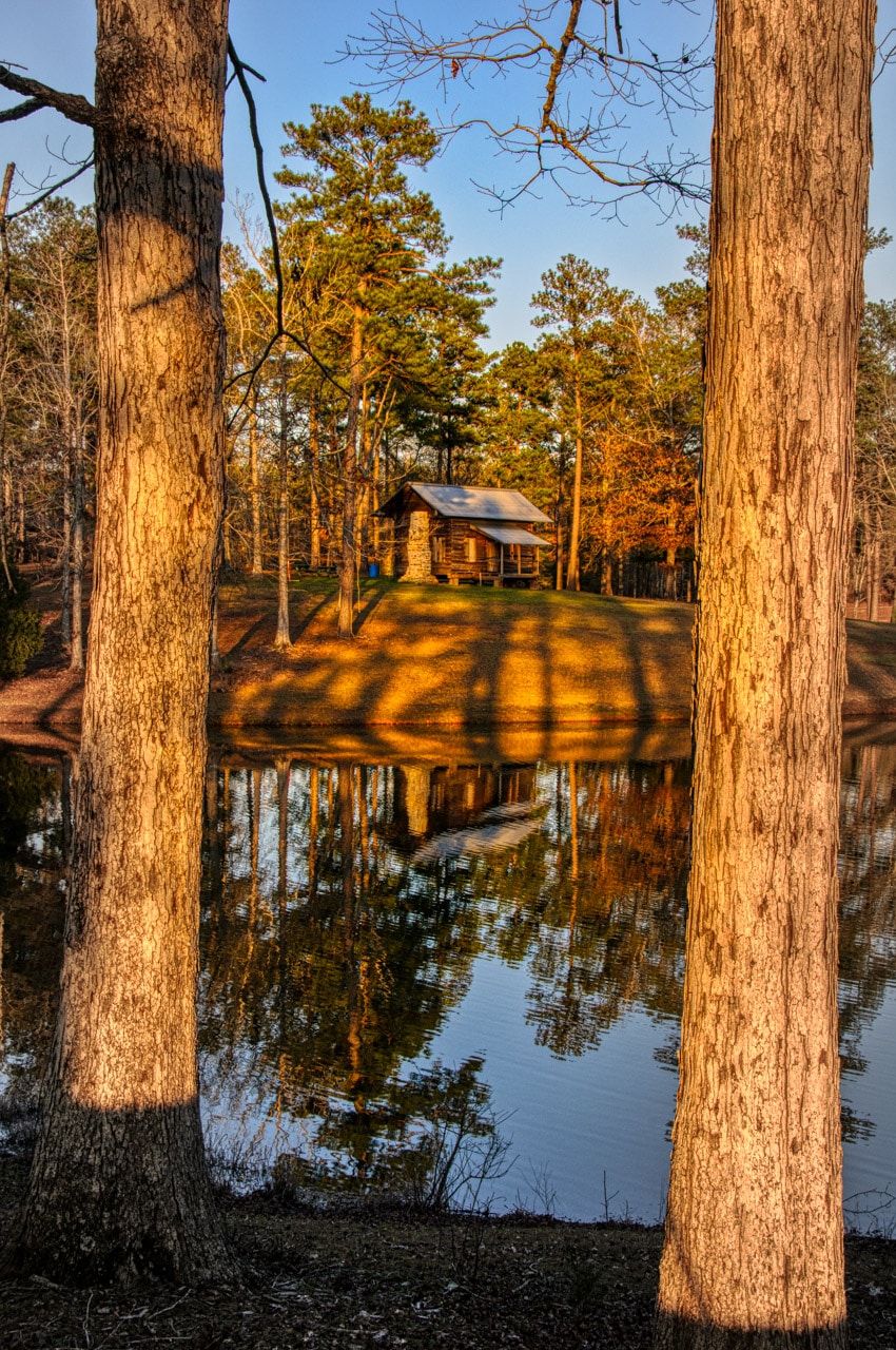 This restored cabin, framed by pine trees, sits near the lake in Evergreen Municipal Park in Evergreen, Alabama.