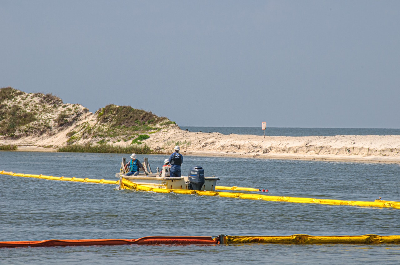 An environmental cleanup crew lays booms along the coast of Dauphin Island, Alabama, in the wake of the Deep Water Horizon spill.