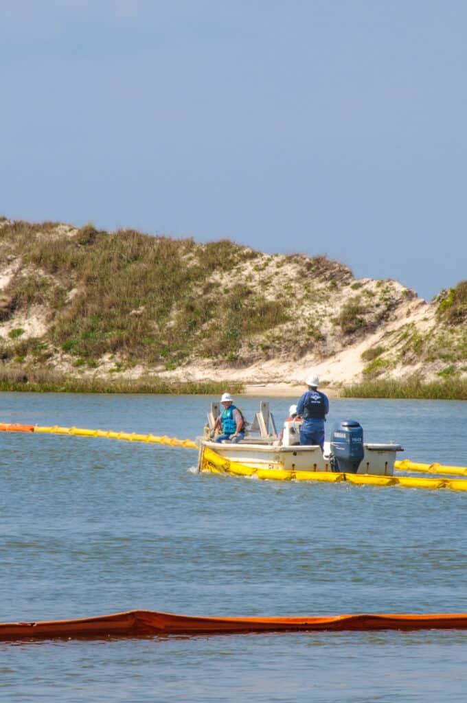 An environmental cleanup crew lays booms along the coast of Dauphin Island, Alabama, in the wake of the Deep Water Horizon spill.