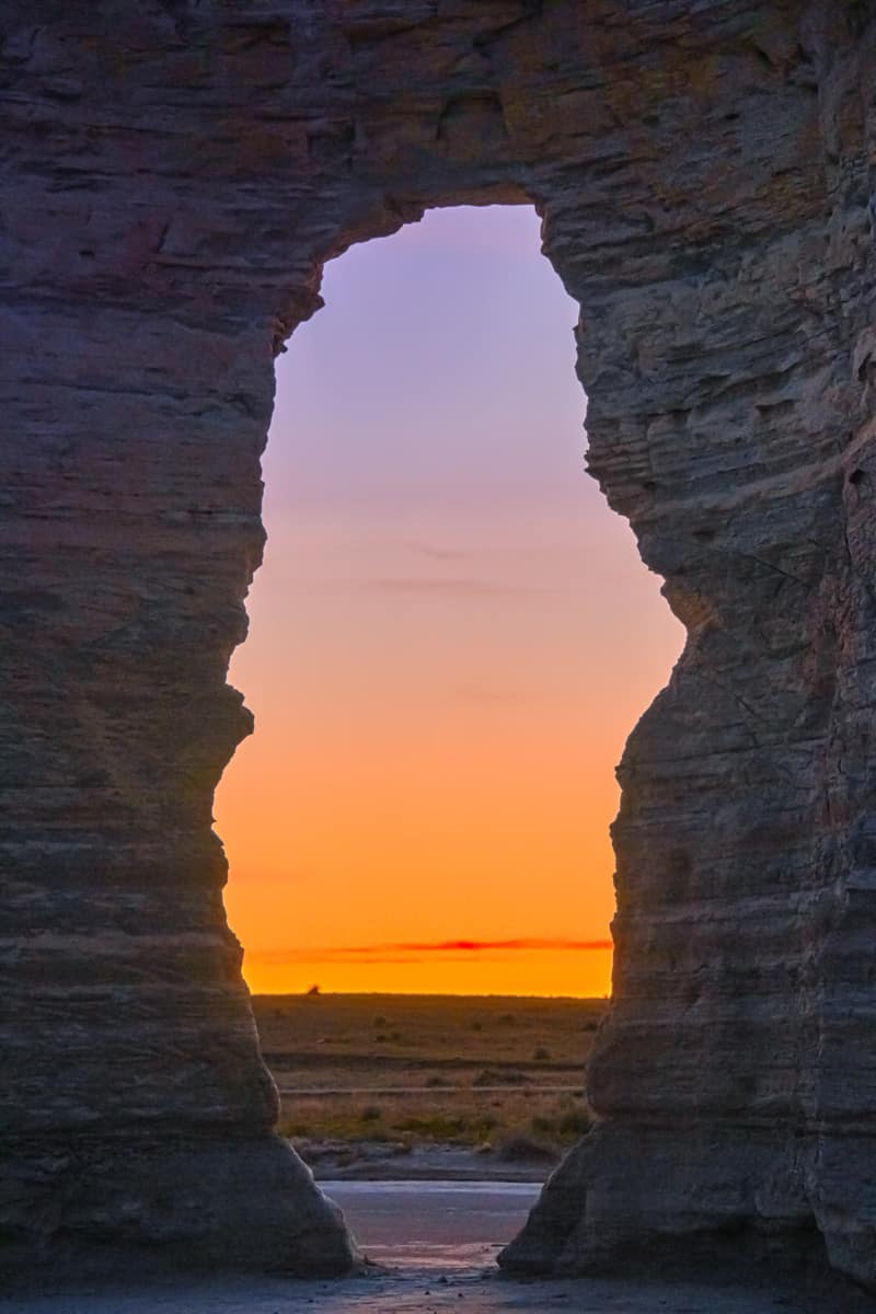 The first light of dawn is visible through a window in one of the formations at Monument Rocks near Oakley, KS.