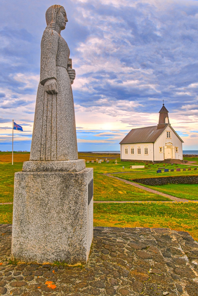 This sculpture in Norwegian granite stands on the grounds of Strandarkirkja. Strandarkirkja loosely translates as "coastal church." The name is fitting as the church overlooks the Atlantic and is visible from far at sea. It is locaded on the southern coast of the Reykjanes peninsula in Iceland.