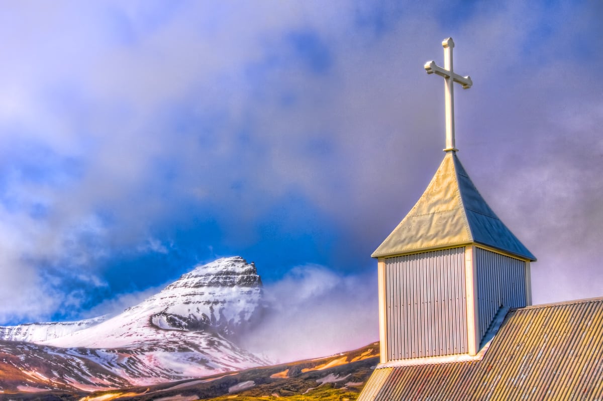 Peak of the mountain Dyrfjoll and the spire of the church Bakkagerðiskirkja in eastern Iceland.