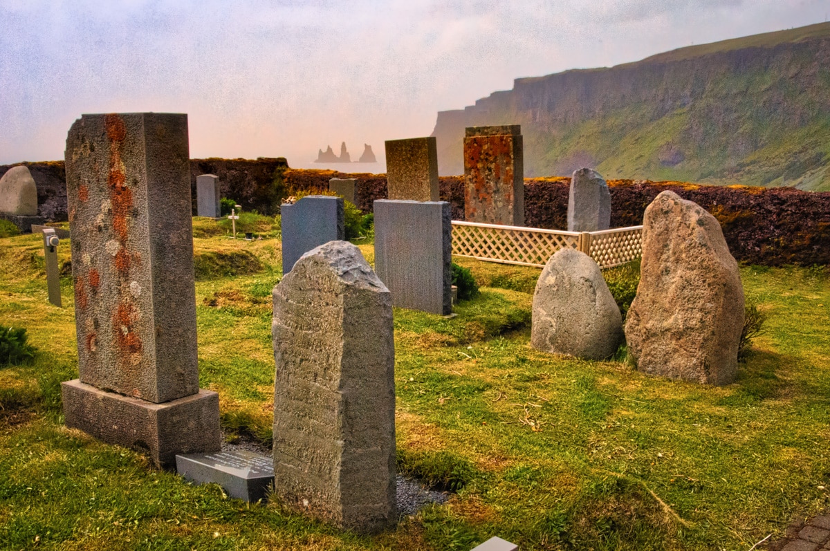Tombstones in the cemetery at Vik in Iceland mimic the sea stacks of the Reynisdrangar spikes.