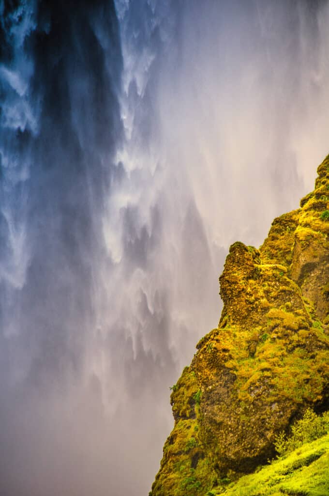 This is a close up of Skógafoss with part of the lava hillside in the foreground. Skógafoss is a waterfall in southern Iceland, along Route 1. It's source is runoff from the glacier Eyjafjallajökull.