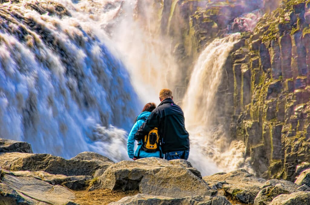 A brave couple stand near the edge of Dettifoss to look down at the plunge pool.