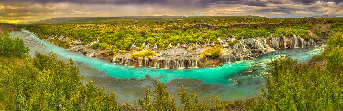 This is one of the most unusual of Iceland's waterfalls. Panoramic view along the waterfall Hraunfossar. Besides being very long, Hraunfossar is unusual in that the fall is along the shore of the main river.
