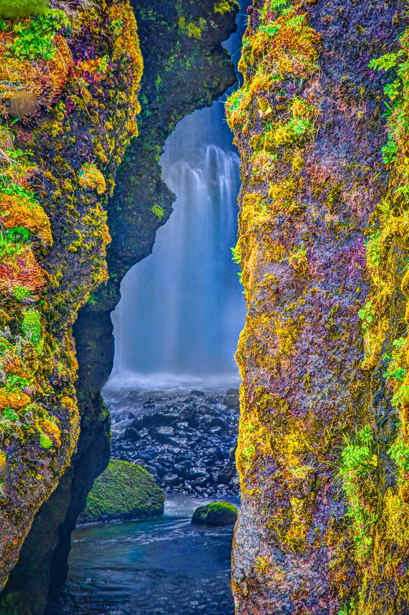 View through a crack in the rocks masking the waterfall Gljúfurárfoss, which lies just north of the fall Seljalandsfoss.