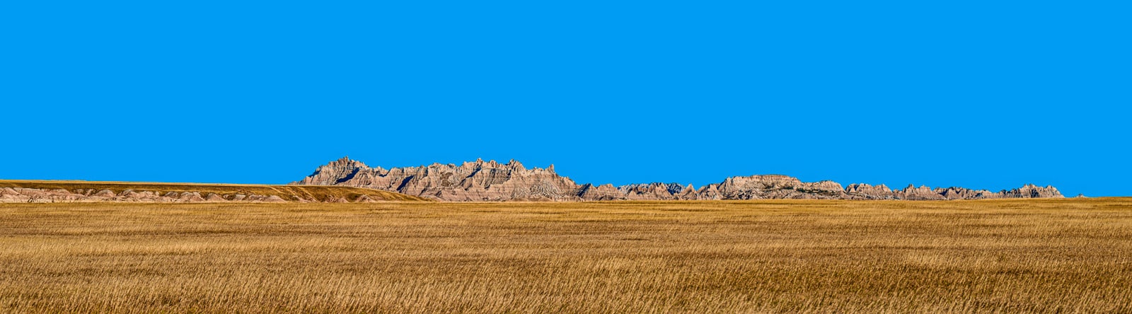 This panorama frames a portion of one of the most famous landmarks in Badlands Natiobnal Park: the Wall. The Wall is a heavily eroded sedementary landscape that exemplified the term badlands. It is roughly sixty miles long and a mile or two wide. In the foregroud is a swath of tallgrass prairie.