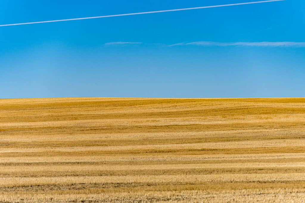 The contrail in the deep blue sky mimics the stripes in the recently harvested field, located along the Enchanted Highway between I-94 and Regent, North Dakota.