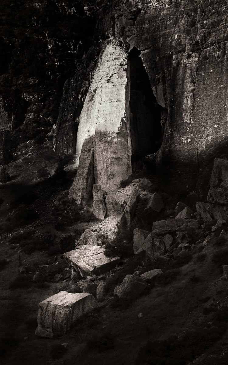 Black and white photo of a column of the Madison limestone with large chunks lying on the ground in front of it.